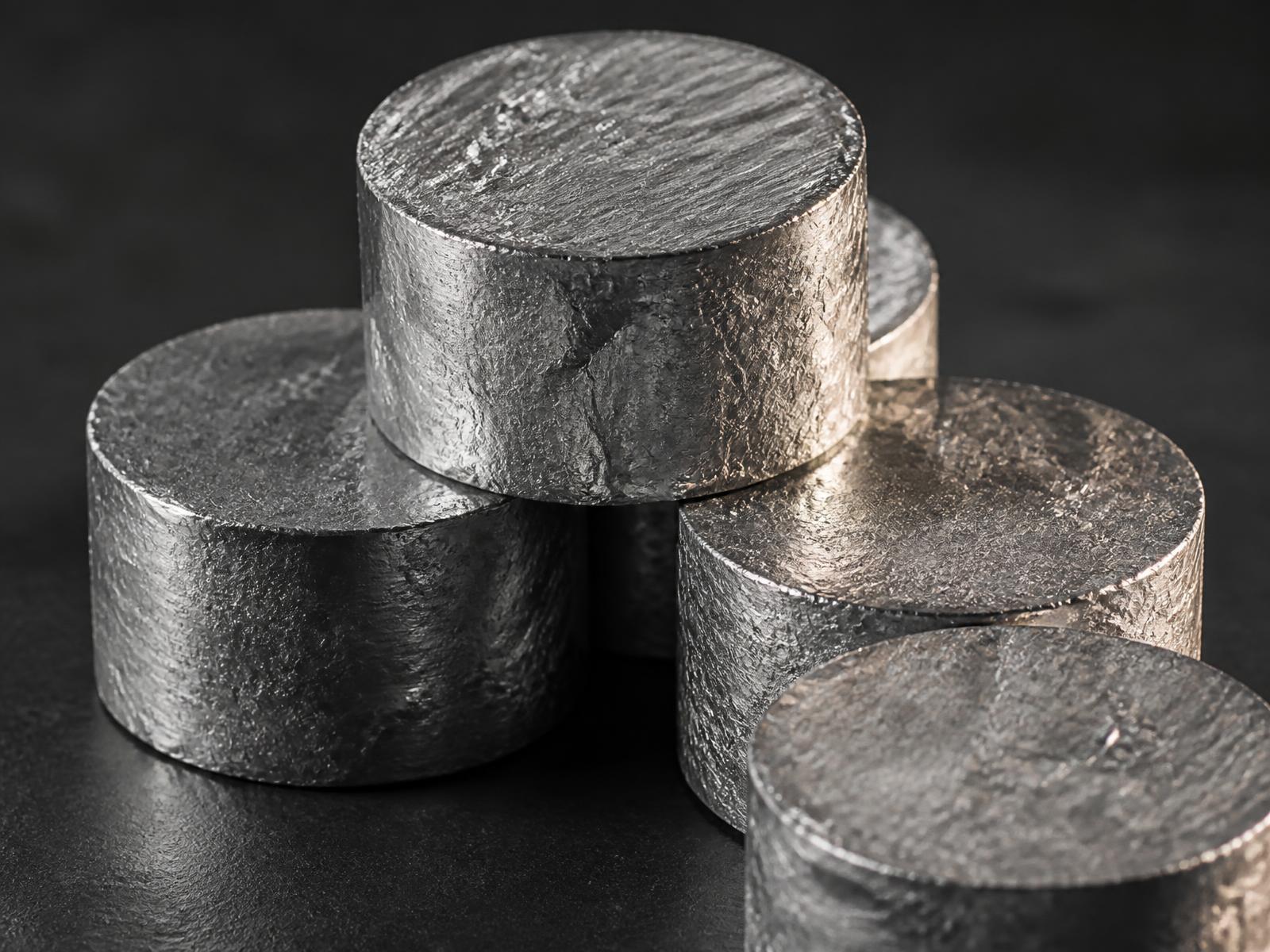 Stacked high-density aluminium pucks on a dark surface